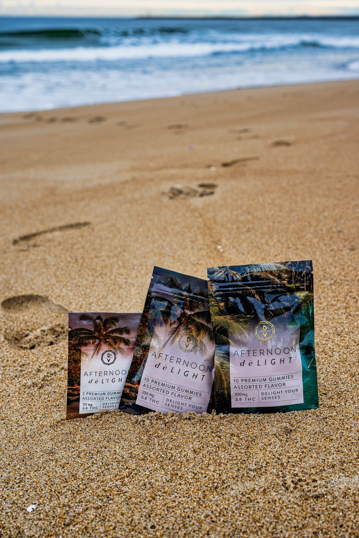 Afternoon deLIGHT ∆8 Gummies in assorted flavors displayed on sandy beach with ocean waves in background